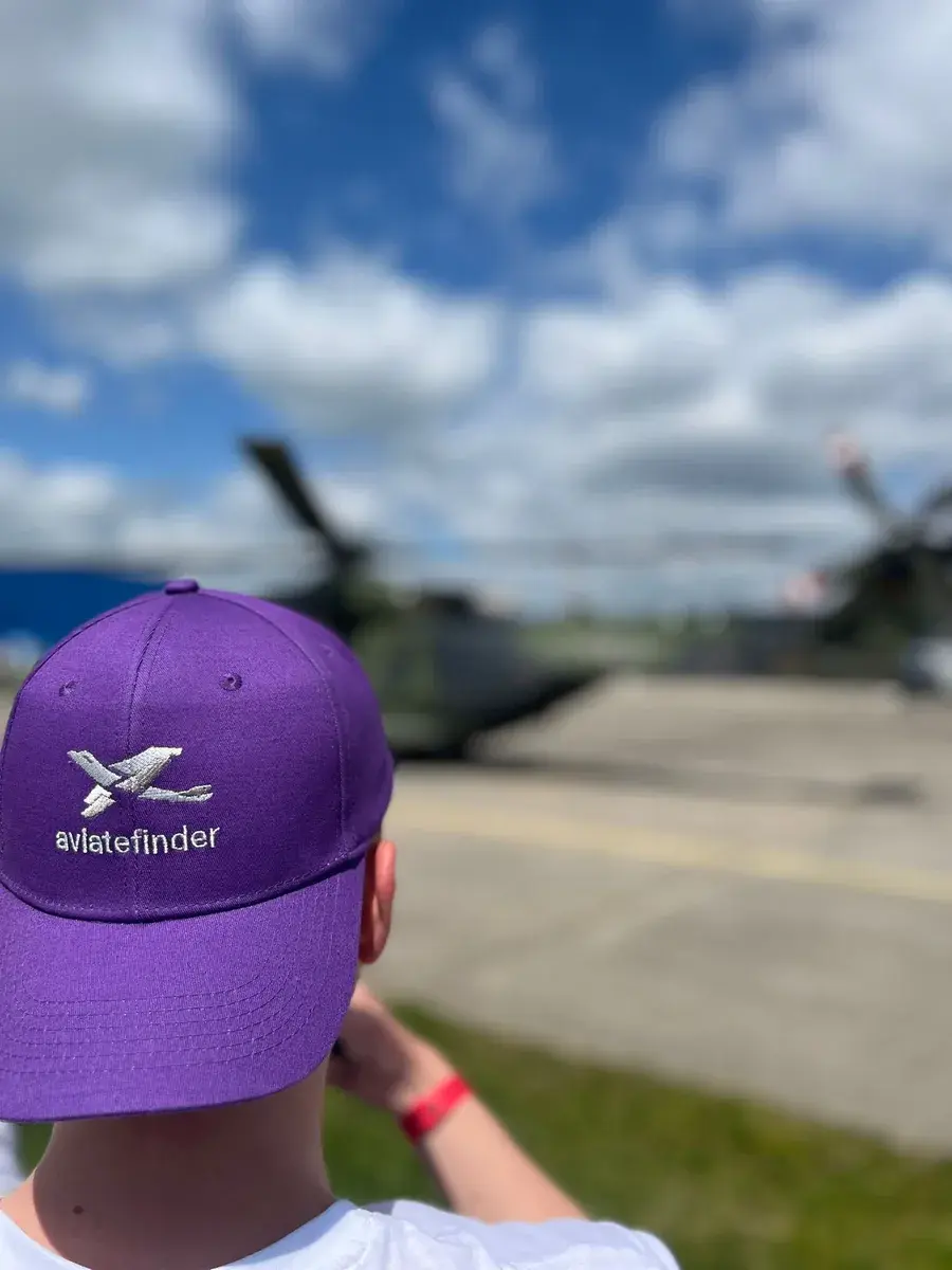 Person mit violetter Aviatefinder-Cap blickt auf abgestellte Flugzeuge